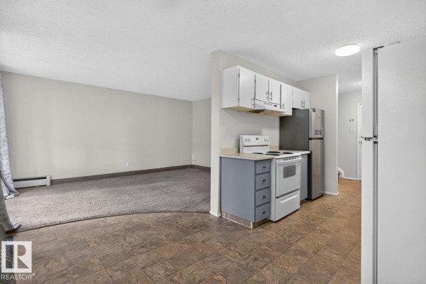 View from kitchen into living room with beige carpet and grey walls. - 237 Woodvale Rd Nw, Edmonton