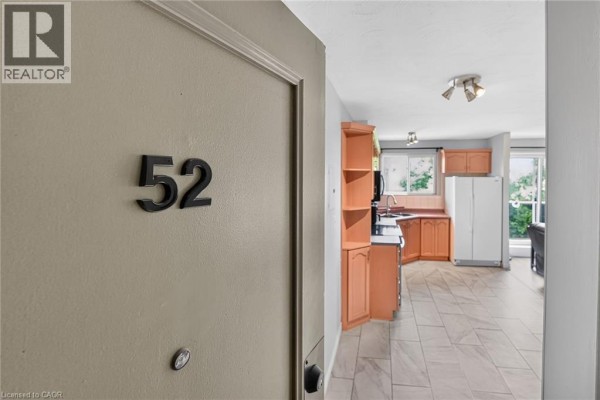 Entrance to unit 52 showing a beige door and a glimpse of the kitchen and living area. - 2373 King Street E Unit# 52, Hamilton