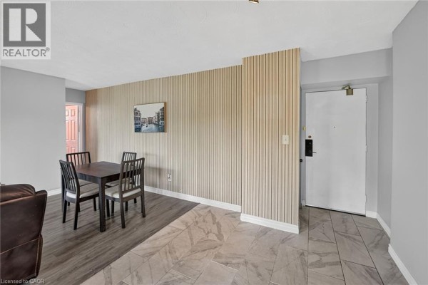 Dining area with a dark wood table and chairs, adjacent to the unit entrance and hallway. - 2373 King Street E Unit# 52, Hamilton