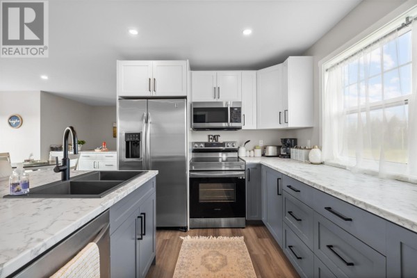 Kitchen featuring white and gray cabinets, a stainless steel refrigerator, and a large window. - 2373 Trout River Road, Breadalbane