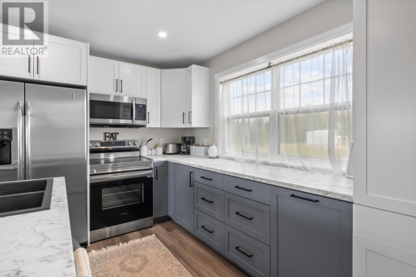 Open-plan kitchen and living area with a large island and view of the countryside. - 2373 Trout River Road, Breadalbane