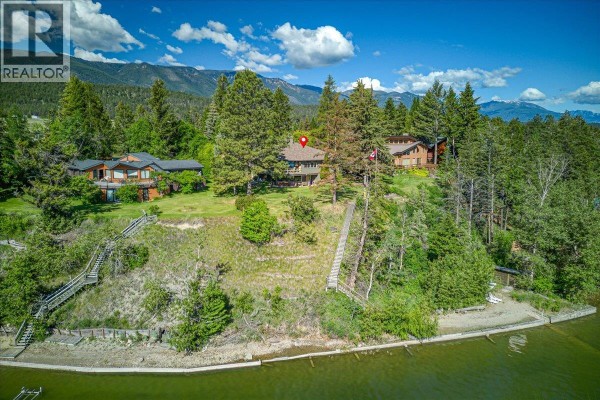 Living room with wood-burning fireplace, vaulted wood ceiling, and sectional sofa. - 2376 Ruault Road, Invermere
