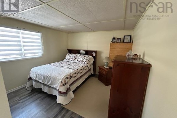 Bedroom with a queen-sized bed, wooden furniture, and grey wood-look laminate flooring. - 2379 Upper Clyde Road, Clyde River
