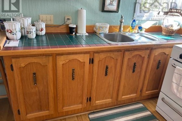 Kitchen with light oak cabinets, a double sink, green tile backsplash, and a white stove. - 2379 Upper Clyde Road, Clyde River
