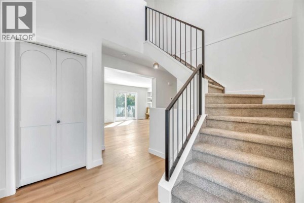 Kitchen featuring wooden cabinetry, white appliances, and tile flooring - 238 Hawktree Bay Nw, Calgary