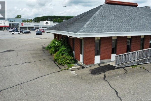 Exterior of a commercial building with red brick walls and asphalt pavement. - 238 Madawaska Road, Grand Sault/grand Falls
