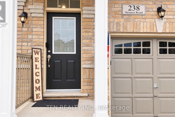 Front door of a beige brick townhouse with a glass pane, black door, and a welcome sign. - 238 Skinner Road, Hamilton