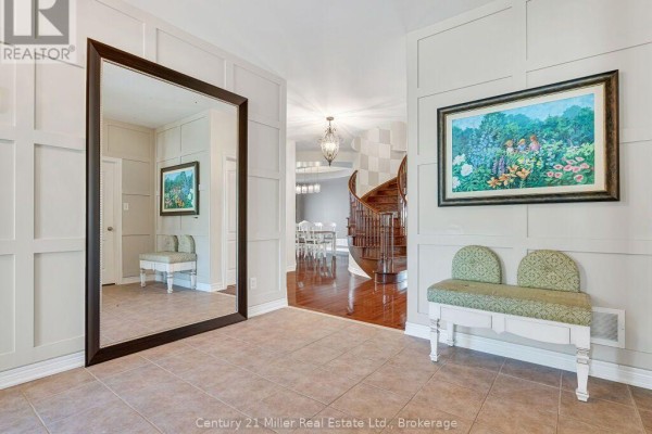 Foyer with a large mirror, bench, painting, and view of dining room and staircase. - 2380 Gladacres Lane, Oakville