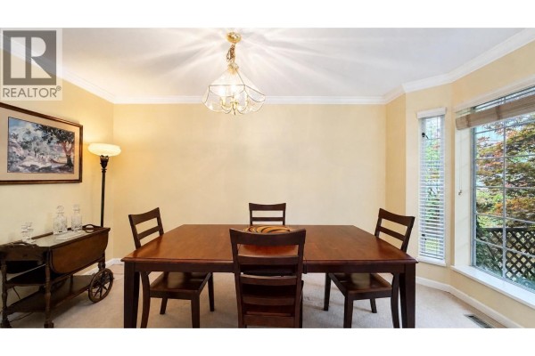 Interior view showing dining area, fireplace, two chairs, and a table with a lamp. - 2387 Quayside Court, Vancouver