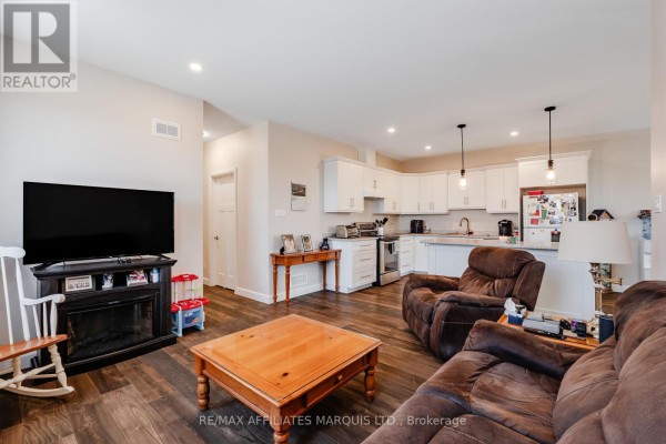 Living room with electric fireplace, TV, sectional, recliner chairs, and open-concept kitchen - 2389 Watson Crescent Cornwall