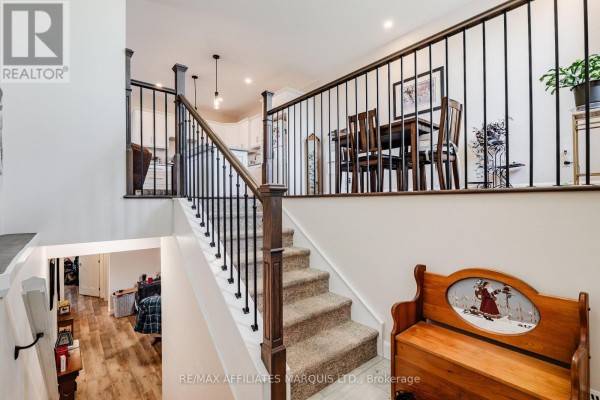 Interior view of a staircase with dark metal railings, leading to a dining area and kitchen. - 2389 Watson Crescent, Cornwall