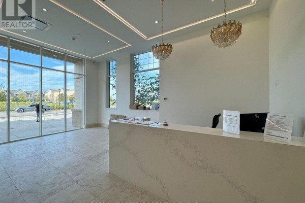 A modern reception desk with a white quartz countertop in a bright lobby with large windows. - 239 - 101 Cathedral High Street, Markham