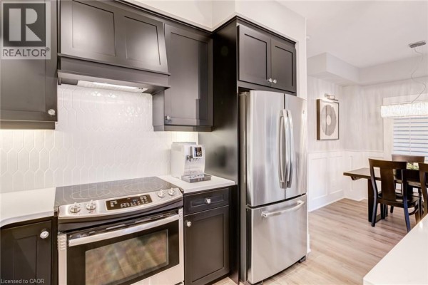 Modern kitchen with black cabinets, stainless steel fridge & range - 239 Cranbrook Street Kitchener