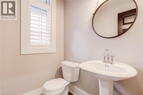 Pedestal sink, round mirror, and toilet with plantation shutters - 239 Cranbrook Street Kitchener