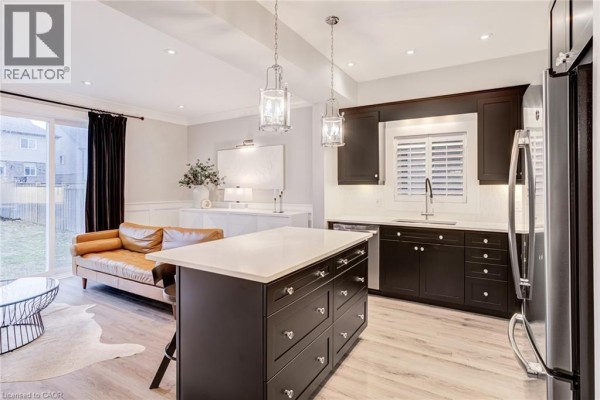 Modern kitchen with island, dark cabinets, white countertops, and leather sofa - 239 Cranbrook Street Kitchener