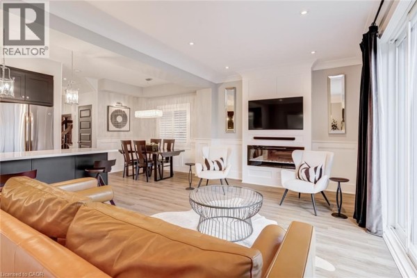 Open concept living area with leather sofa, fireplace, and TV - 239 Cranbrook Street Kitchener