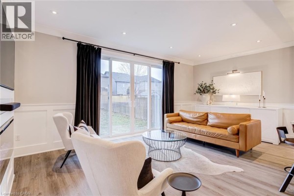 Leather sofa and accent chairs in a modern living room with glass coffee table and backyard view - 239 Cranbrook Street Kitchener