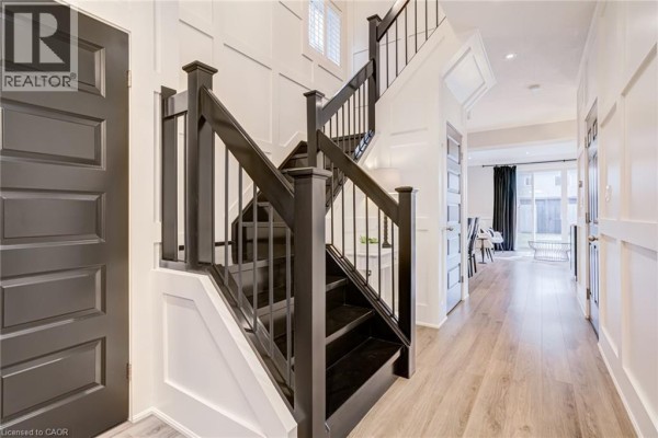 Hallway with dark wood staircase, wainscoting, and hardwood floors - 239 Cranbrook Street Kitchener