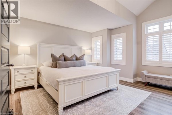 Primary bedroom with vaulted ceiling, king bed, bench, and shutters - 239 Cranbrook Street Kitchener