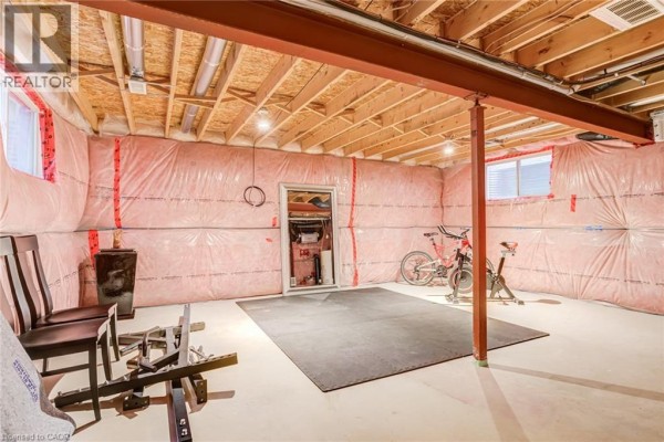 Basement gym area with exercise bike, weight rack & exposed joists - 239 Cranbrook Street Kitchener