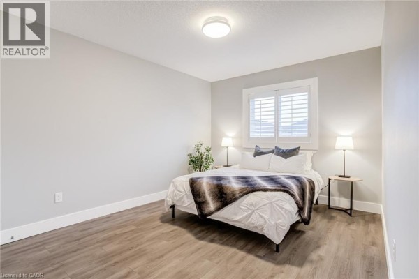 Bedroom with queen bed, plaid blanket, bedside lamps, and plantation shutters - 239 Cranbrook Street Kitchener