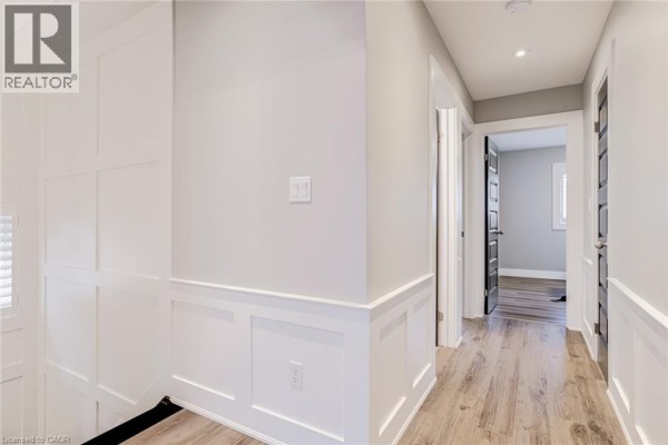 Hallway with wainscoting, hardwood floors, and black interior doors - 239 Cranbrook Street Kitchener