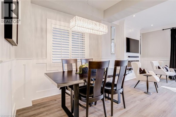 Dark wood dining table and chairs near plantation shutters, with white armchairs visible in adjacent living space - 239 Cranbrook Street Kitchener