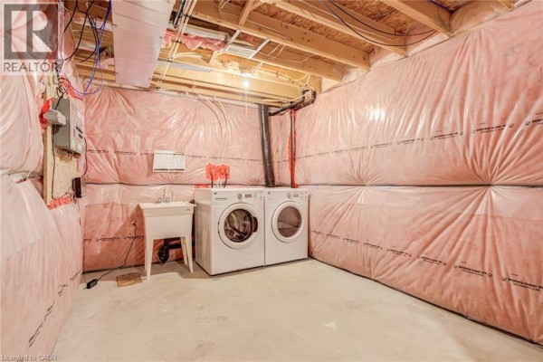 Washing machine, dryer, and utility sink in unfinished basement laundry room - 239 Cranbrook Street Kitchener