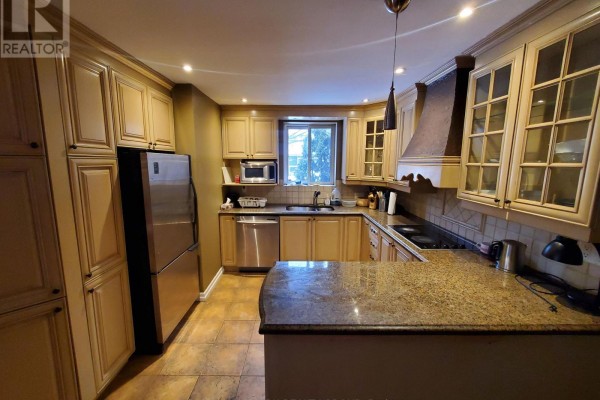 U-shaped kitchen with ample light wood cabinetry, granite countertops, and stainless steel refrigerator. - 239 Dale Avenue, Ottawa