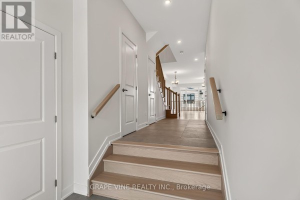 Interior foyer looking down a hallway with light wood stairs and doors. - 239 Monticello Avenue, Ottawa