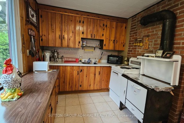 Vintage kitchen with wood cabinets, brick chimney, and stove - 2392 Lakeshore Drive Ramara