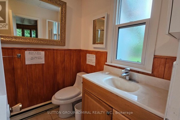 Toilet, sink, and wood paneling in a bathroom - 2392 Lakeshore Drive Ramara