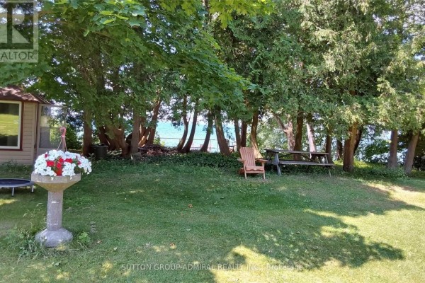 Yard with trees, picnic table, Adirondack chair, and water view - 2392 Lakeshore Drive Ramara