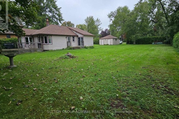Grassy backyard with a bird bath, fire pit, and a detached garage. - 2392 Lakeshore Drive, Ramara