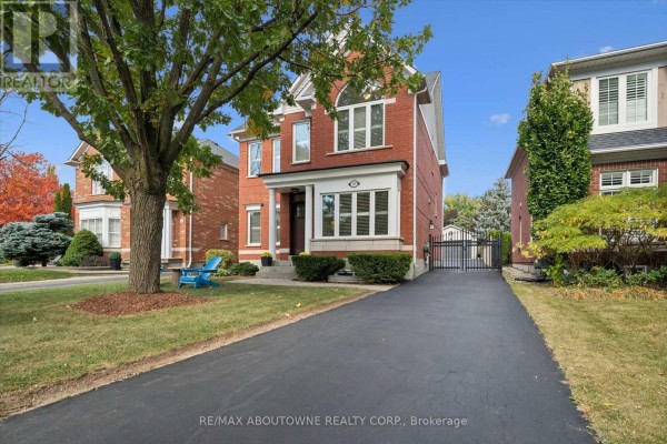 Exterior view of a red brick house with a long driveway and a black metal gate. - 2397 Ennerdale Road, Oakville