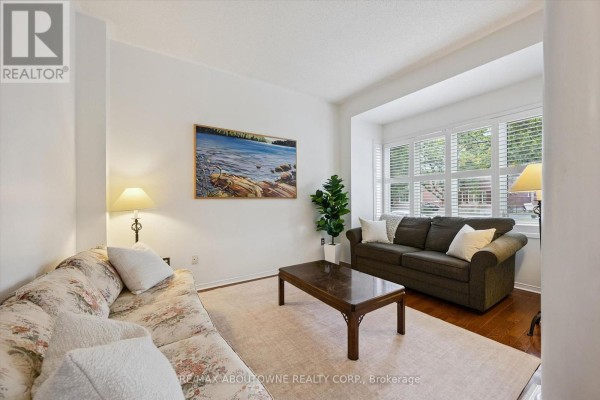 Living room with a large bay window, two sofas, a coffee table, and hardwood floors. - 2397 Ennerdale Road, Oakville