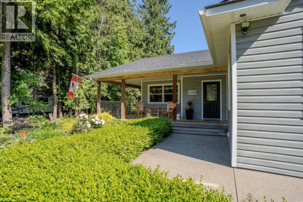 Aerial view of a gray bungalow with a three-car garage and surrounding forest. - 2399 Hillen Crescent, Magna Bay