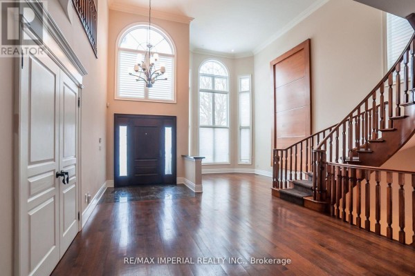 Two-story stone house with a symmetrical facade, double garage doors, and snow-covered lawn. - 23a Mackay Drive, Richmond Hill