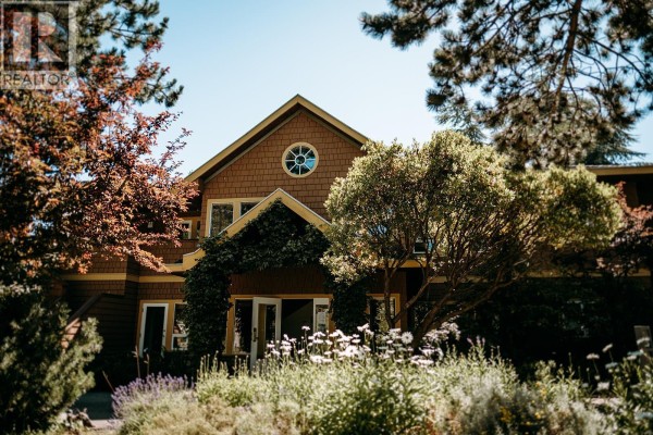Exterior view of a brown building with a round window and trees. - 23b 134 Madrona Road, Galiano Island