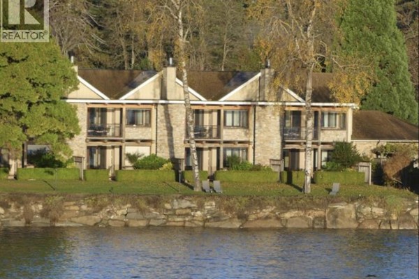 View of a stone building with multiple units facing a body of water. - 23b 134 Madrona Road, Galiano Island