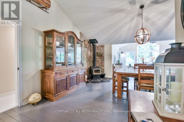 Dining area with wooden table and chairs, stone fireplace, and a large hutch. - 24 - 1213 Camp Jackson Road, Muskoka Lakes
