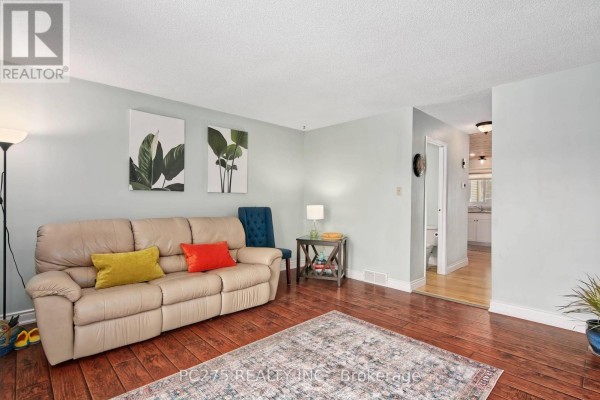 Wooden deck with railing, table, chairs, and flowering trees in the background. - 24 - 301 Carlow Road, Central Elgin
