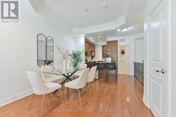 Dining area with glass table, chairs, and a kitchen island with stools. - 24 - 70 Byng Avenue, Toronto