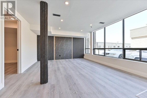 Commercial space with large windows, dark wood accent wall, and light grey flooring. - 24 - 7171 Torbram Road, Mississauga
