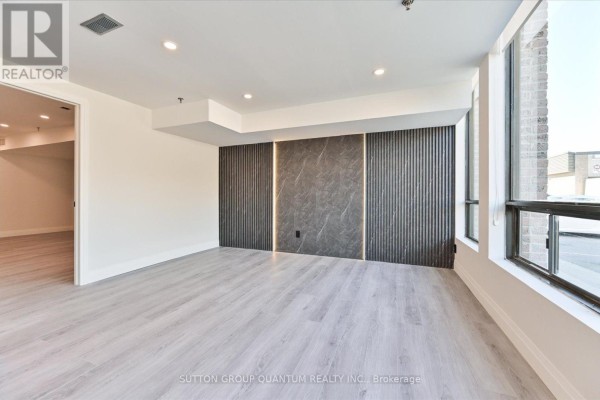 Empty commercial space with light grey flooring, large windows, and decorative wall panels. - 24 - 7171 Torbram Road, Mississauga