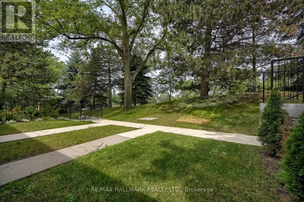 Side view of red brick townhouses with dark sloped roofs and green grass. - 24 - 94 George Henry Boulevard, Toronto