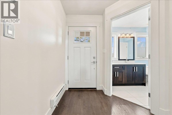 Interior hallway with white door, wood floor, and doorway to a bathroom. - 24 10151 240 Street, Maple Ridge