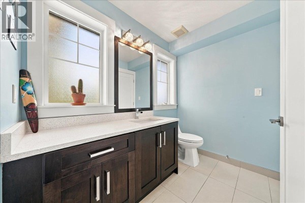 Powder room with light blue walls, dark wood vanity, white countertop, and toilet. - 24 10151 240 Street, Maple Ridge