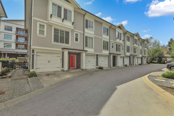 Exterior view of a townhouse complex with gray siding and attached garages. - 24 14499 64 Avenue, Surrey