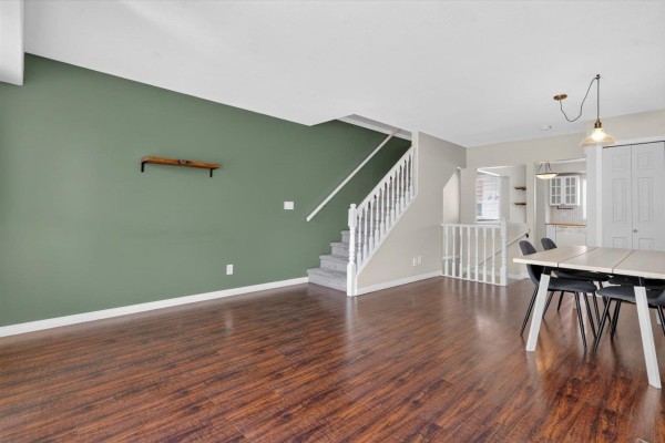 Interior entryway with a green front door, dark tile flooring, and a wooden staircase. - 24 9470 Hazel Street, Chilliwack Proper East, Chilliwack